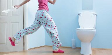 A woman wearing pjs running to a toilet.